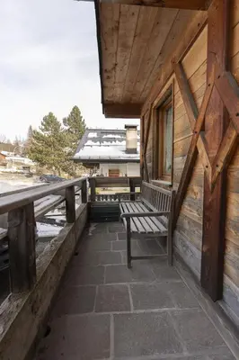 a bench sitting on the porch of a cabin at Casa Col 3, graziosa e confortevole a due passi dalle piste in Cortina dʼAmpezzo