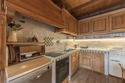 a kitchen with wooden cabinets and a sink at Casa Varentin, in the center of Cortina in Cortina dʼAmpezzo
