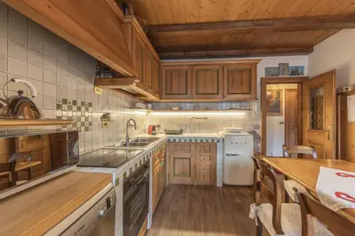 a kitchen with wooden cabinets and a white refrigerator at Casa Varentin, in the center of Cortina in Cortina dʼAmpezzo