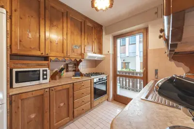 a kitchen with wooden cabinets and a microwave at Casa Verzi, comoda e confortevole in pieno centro in Cortina dʼAmpezzo