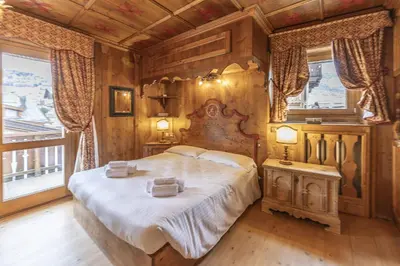 a bedroom with a large bed in a room with wooden walls at Casa Verzi, comoda e confortevole in pieno centro in Cortina dʼAmpezzo