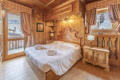 a bedroom with a large bed in a room with wooden walls at Casa Verzi, comoda e confortevole in pieno centro in Cortina dʼAmpezzo