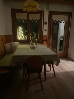 a dining room with a table and a christmas tree in the window at Zirmo mountain home in Carano