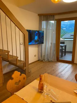 a living room with a table and a television on a wall at dolomites view apartment 2 in Rasun di Sopra