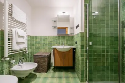 a green tiled bathroom with a sink and a toilet at Chalet Chiave - Prenotazioni Dirette Dolomiti Skyline in Cortina dʼAmpezzo