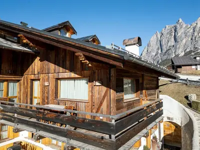a wooden house in the mountains with mountains in the background at Chalet Chiave - Prenotazioni Dirette Dolomiti Skyline in Cortina dʼAmpezzo