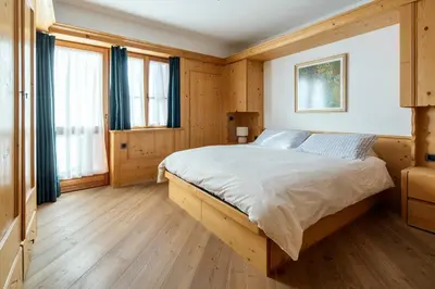 a bedroom with a large bed with wooden floors and windows at Chalet Chiave - Prenotazioni Dirette Dolomiti Skyline in Cortina dʼAmpezzo