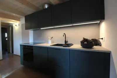 a kitchen with black cabinets and a sink at Casa Tomà Mountain View Cortina in San Vito di Cadore