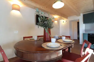 a dining room with a wooden table and a vase with flowers at Casa Tomà Mountain View Cortina in San Vito di Cadore