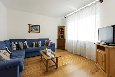 a living room with a blue couch and a tv at Tai Bedoes in Moena