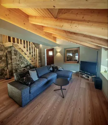 a living room with a blue couch and wooden ceilings at Selva loft in Selva di Cadore