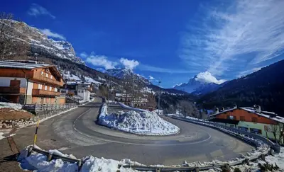 a winding road with snow on the side of a mountain at Selva loft in Selva di Cadore