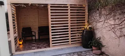 a patio with a wooden fence and two chairs at Blätterbett - letto di foglie in Bolzano