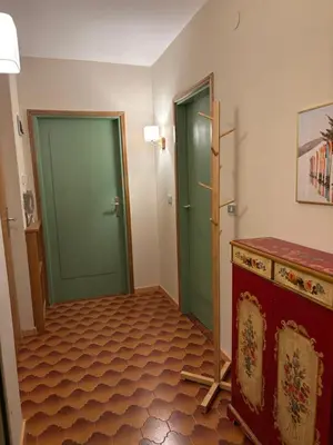 a hallway with two green doors and a tile floor at Passo Carezza Club Apartment in Carezza al Lago