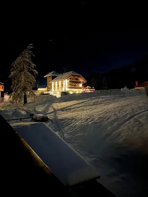 a snowboard sitting in the snow in front of a house at Passo Carezza Club Apartment in Carezza al Lago