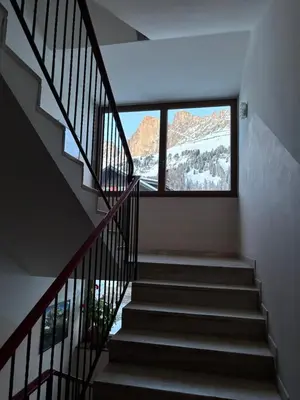 a staircase in a house with a large window at Passo Carezza Club Apartment in Carezza al Lago