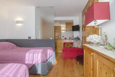 a bedroom with a bed and a kitchen with a sink at Monolocale in centro a Cortina in Cortina dʼAmpezzo
