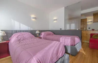 a bedroom with two beds with pink blankets at Monolocale in centro a Cortina in Cortina dʼAmpezzo