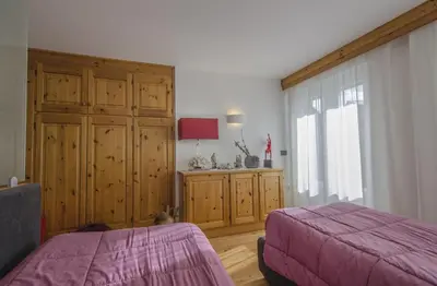 a bedroom with a purple bed and a large window at Monolocale in centro a Cortina in Cortina dʼAmpezzo