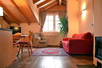 a living room with a red couch and chairs at Casa Micol in Moena