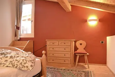 a bedroom with a bed and a dresser and a window at Casa Micol in Moena