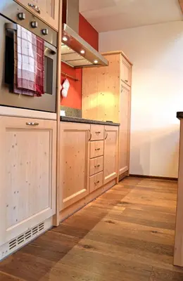 a kitchen with wooden cabinets and wooden floors at Casa Micol in Moena