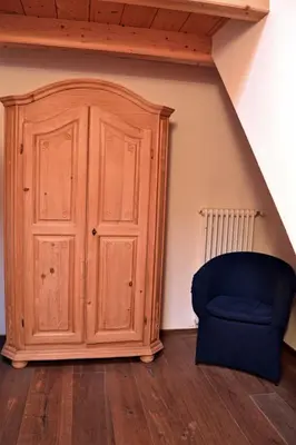 a wooden cabinet and a blue chair in a room at Casa Micol in Moena