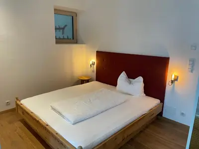 a small bedroom with a bed with a wooden headboard at Appartamento con terrazza in Bolzano