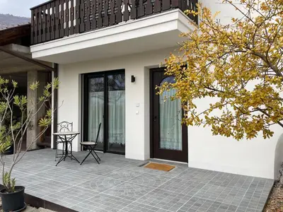 a front porch of a house with a black door at Appartamento con terrazza in Bolzano