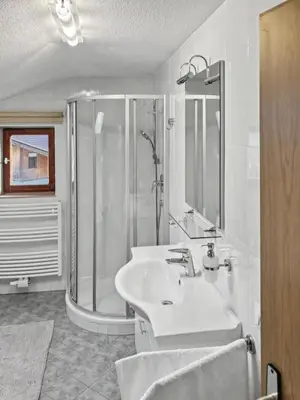 a white bathroom with a shower and a sink at Ruhige Dachwohnung mit Bergblick - Passeiertal in Saltusio
