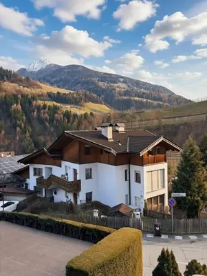 a large white house with a mountain in the background at Ruhige Dachwohnung mit Bergblick - Passeiertal in Saltusio