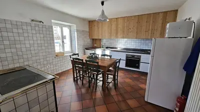 a kitchen with a table and chairs and a refrigerator at Majon jal Toni in Vigo di Fassa