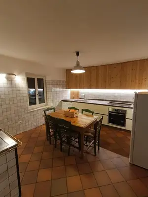 a kitchen with a table with chairs and a refrigerator at Majon jal Toni in Vigo di Fassa