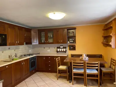 a kitchen with wooden cabinets and a table and chairs at Appartamento Agordo in un borgo antico in Agordo