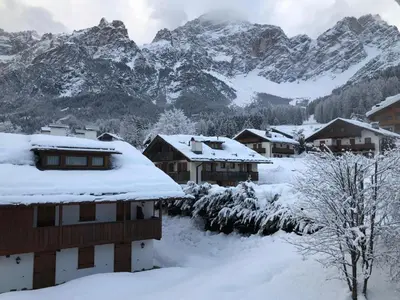 a village covered in snow with mountains in the background at Appartamento cozy tra le montagne in San Vito di Cadore