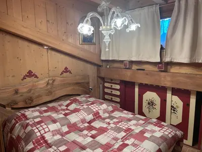 a bedroom with a bed and a chandelier at Appartamento cozy tra le montagne in San Vito di Cadore