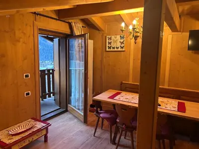 a dining room with a table and a balcony at Appartamento cozy tra le montagne in San Vito di Cadore