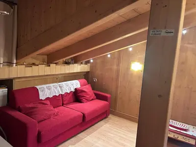 a living room with a red couch in a room at Appartamento cozy tra le montagne in San Vito di Cadore