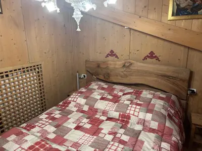 a bedroom with a bed with a wooden wall at Appartamento cozy tra le montagne in San Vito di Cadore