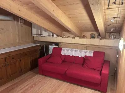 a living room with a red couch in a kitchen at Appartamento cozy tra le montagne in San Vito di Cadore