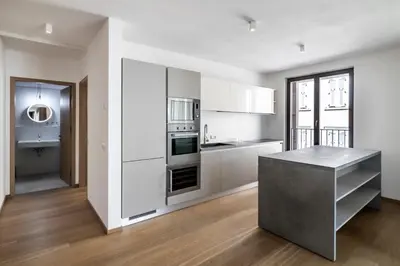 a kitchen with white cabinets and a table in a room at Stay COOPER l MAVIK Suite & Attic in Bolzano