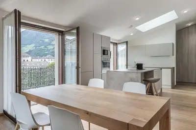 a kitchen and dining room with a wooden table and chairs at Stay COOPER l MAVIK Suite & Attic in Bolzano