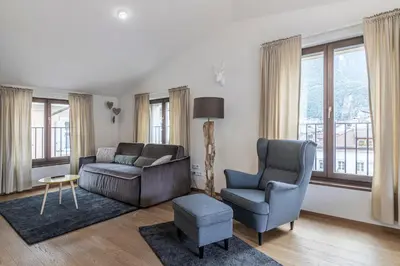 a living room with a couch and chairs and windows at Stay COOPER l MAVIK Suite & Attic in Bolzano