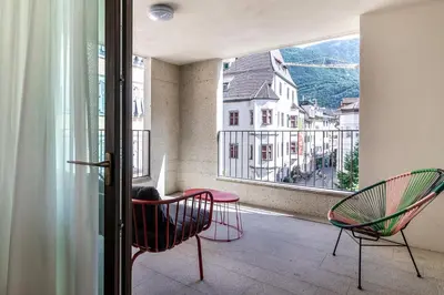 a balcony with two chairs and a table and a window at Stay COOPER l MAVIK Suite & Attic in Bolzano