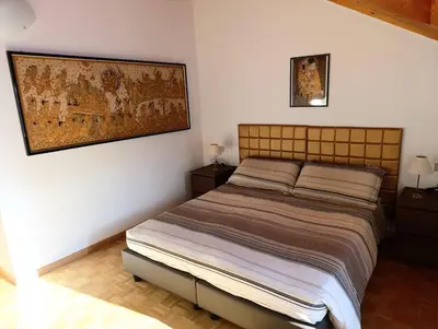 a bedroom with a bed and a painting on the wall at Casa Sergio in Ziano di Fiemme