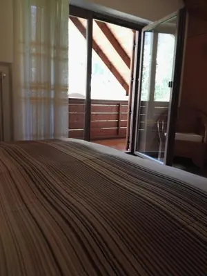 a bed in a room with a large window at Casa Sergio in Ziano di Fiemme