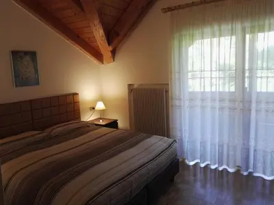 a bedroom with a bed and a large window at Casa Sergio in Ziano di Fiemme