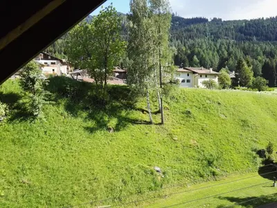 a green field with trees and houses on a hill at Casa Sergio in Ziano di Fiemme