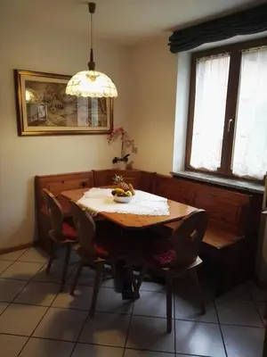 a dining room table with chairs and a chandelier at Casa Sergio in Ziano di Fiemme