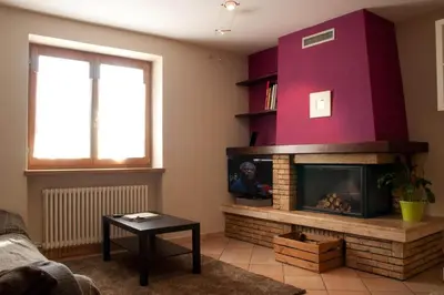 a living room with a fireplace and a red wall at Casa Dolci by Sunhome Fiemme in Tesero